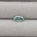 1.23 Carat Green Marquise Cut Loose Diamond placed on a light gray fabric background.