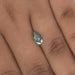 1.23 Carat Green Marquise Cut Loose Diamond placed on a finger, highlighting its unique green color and elongated shape against the skin.