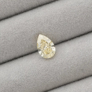 2.17 Carat Fancy Yellow Pear Cut Loose Diamond displayed on a gray cushioned surface, showcasing its elegant shape and yellow color.